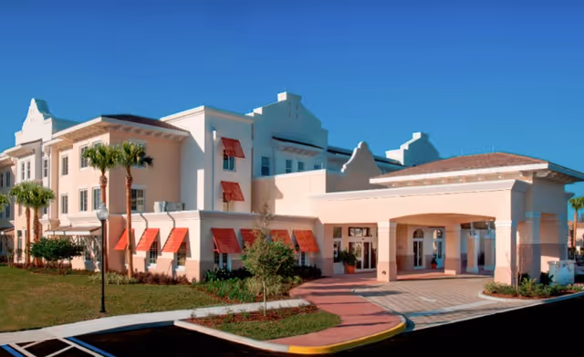 Exterior view of Encore at Avalon Park Assisted Living building with peach walls and red awnings.