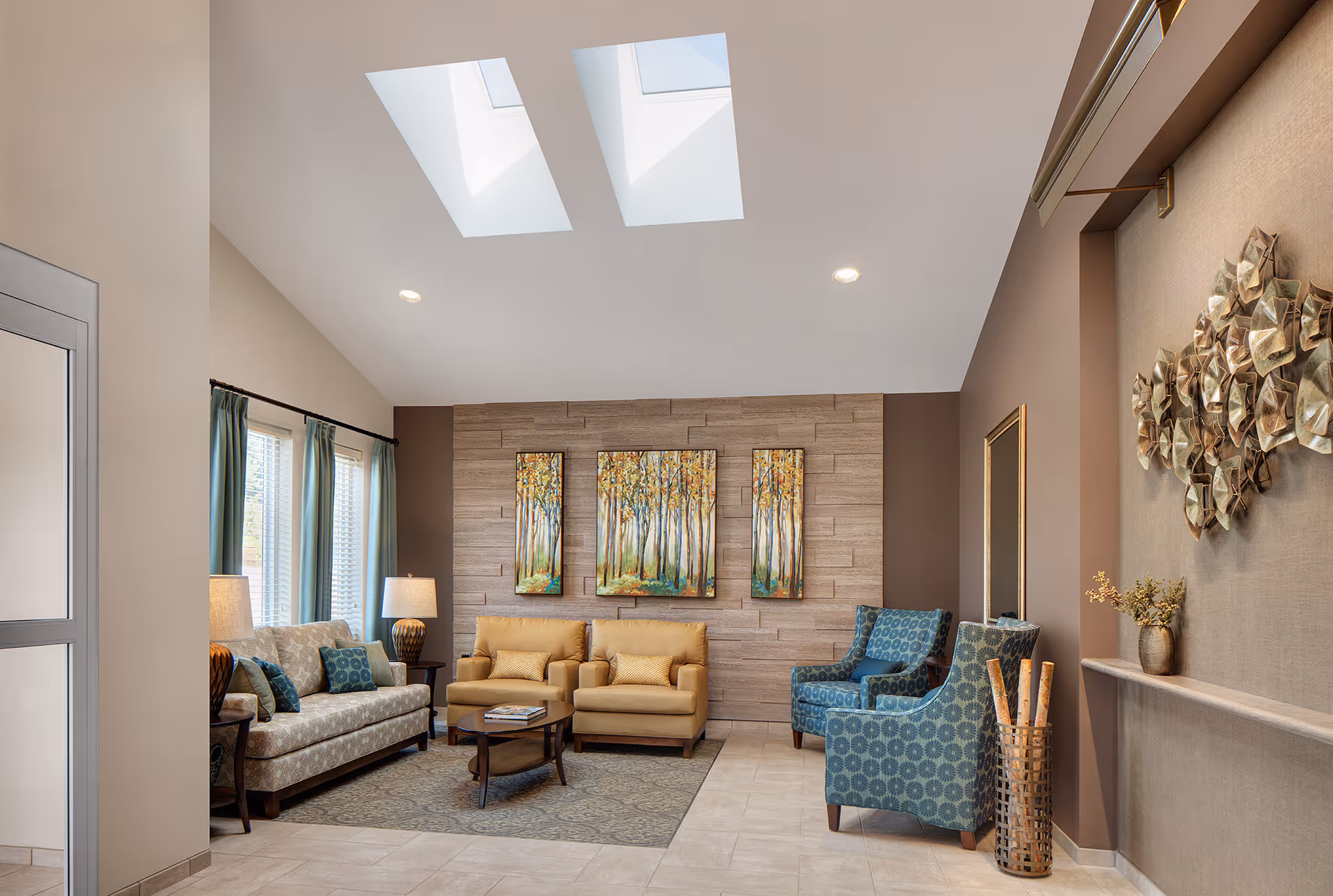 Bright, modern sitting room with sofas, armchairs, skylights, and decorative wall art.