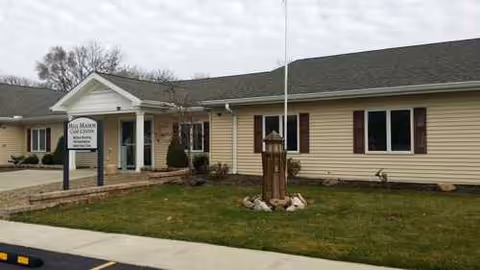 A single-story Mill Manor Care Center exterior with entrance sign and lawn.