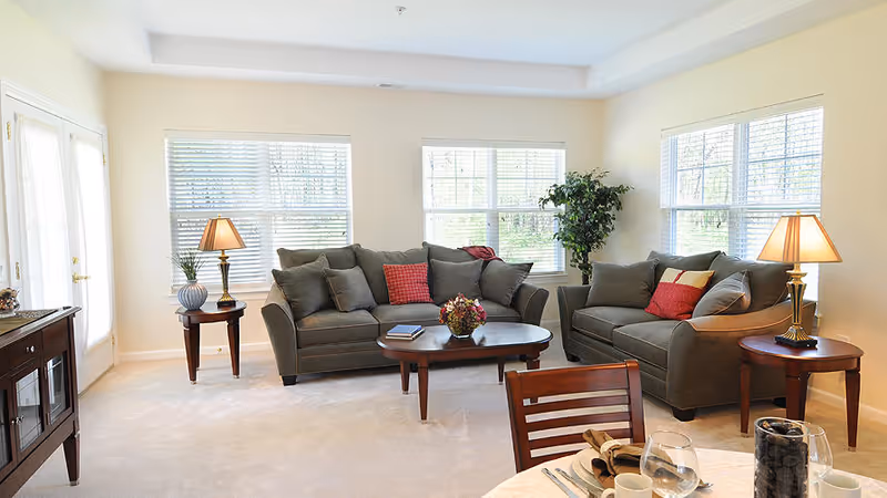 Bright living room with two sofas, a coffee table, side tables with lamps, and large windows letting in natural light.