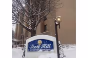 Snowy exterior of Scott Hill Retirement Community with a blue sign.
