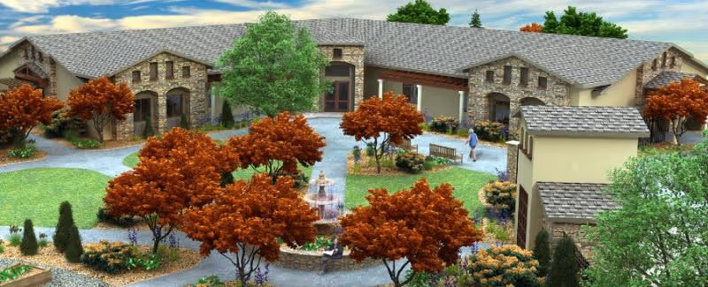 Exterior view of a senior living facility named Landmark Memory Care featuring a large building with stone and beige walls, surrounded by landscaped gardens with green grass, orange-leaved trees, shrubs, and a central fountain. A person is walking on a pathway near the entrance.
