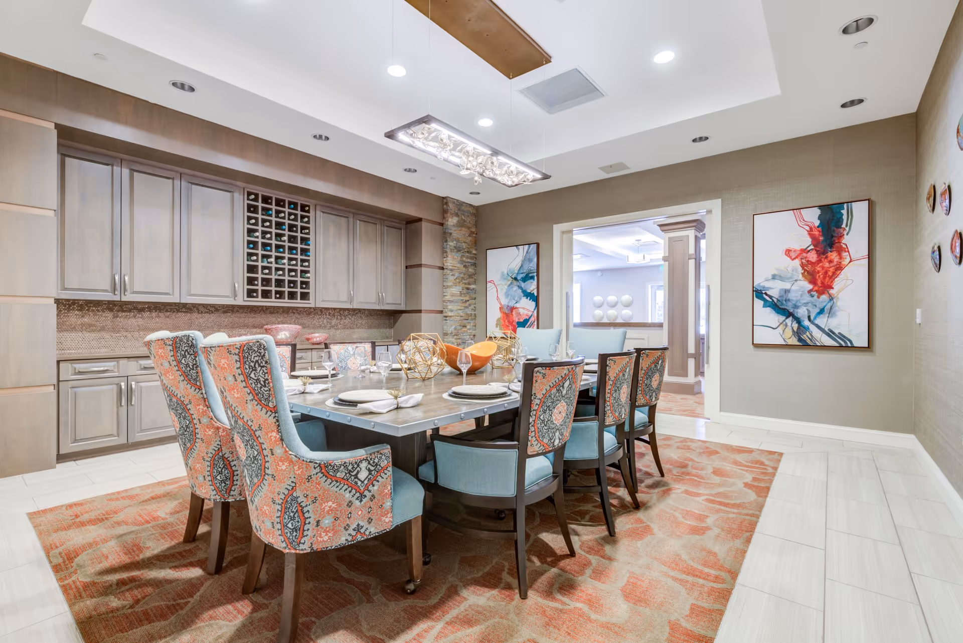 Elegant dining room with a long set table, patterned upholstered chairs, built-in cabinets and contemporary artwork on the walls.