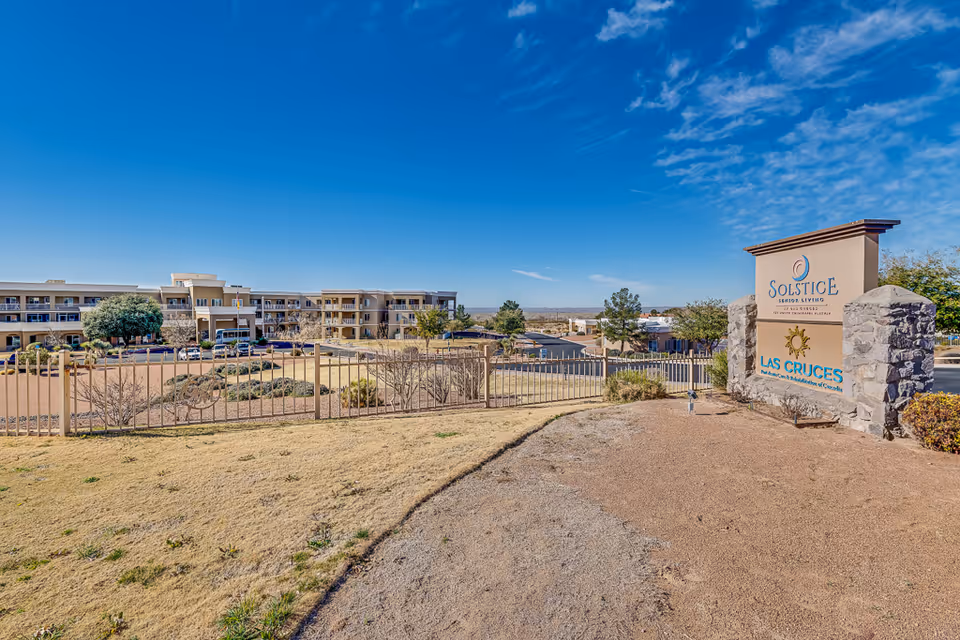 Exterior view of the Solstice Senior Living at Las Cruces building with its entrance sign under a clear blue sky.