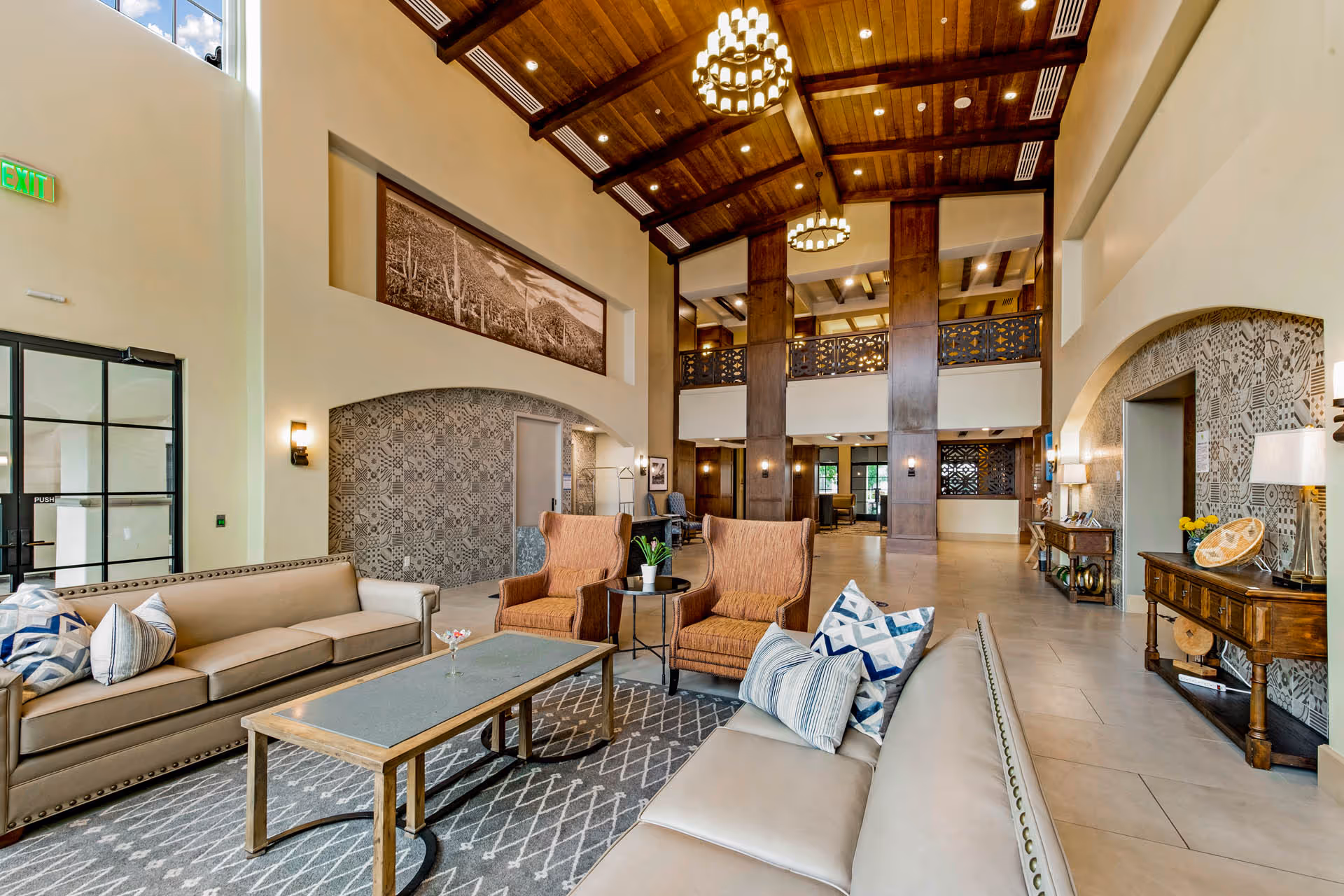 Spacious high-ceilinged lobby lounge with sofas, armchairs, coffee tables, wood-beamed ceiling and chandeliers.