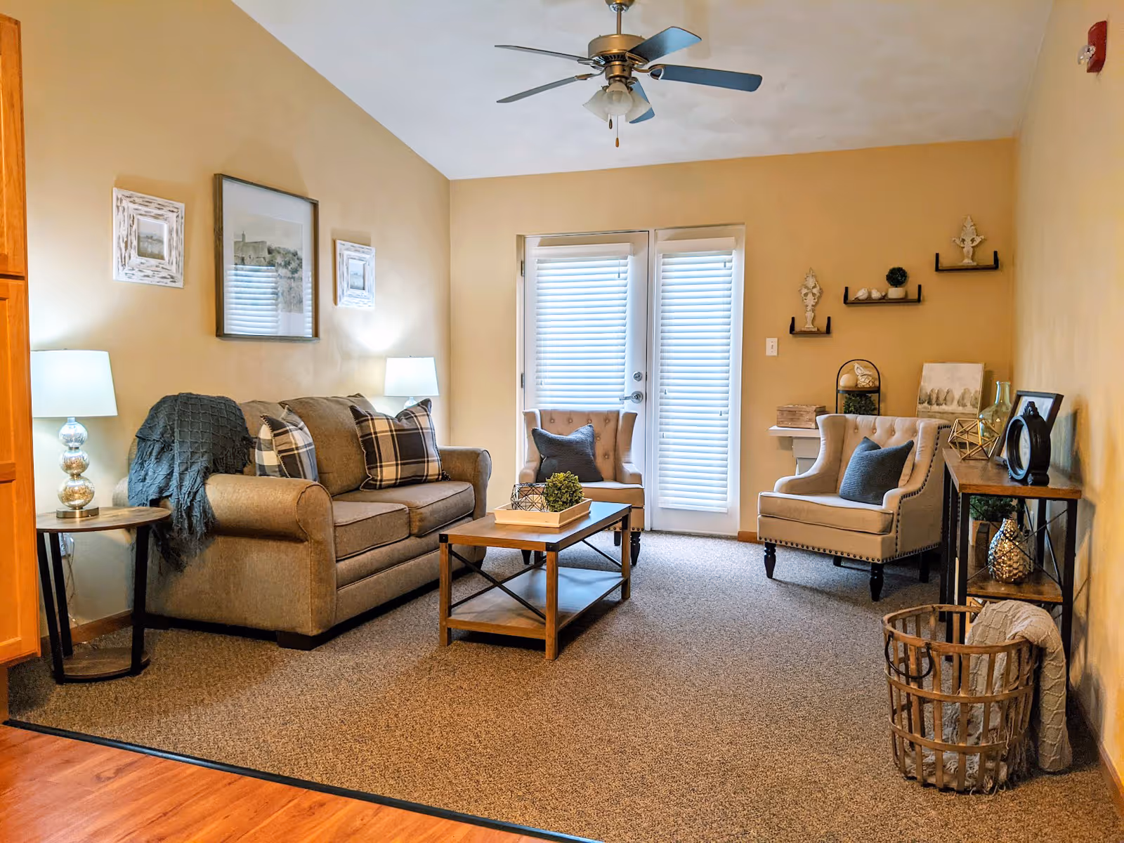 Cozy living room with a sofa, two armchairs, coffee table, side tables and French doors with blinds.