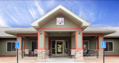 Exterior view of Ely Carefree Living building entrance with pillars, stone bases, and handicap signs.
