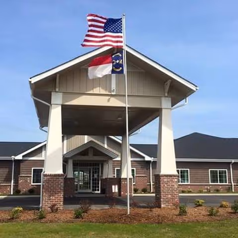 Exterior view of Gates House senior living entrance with American and state flags.
