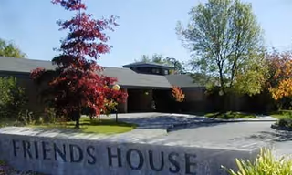 Front view of Friends House senior living facility with sign and trees.