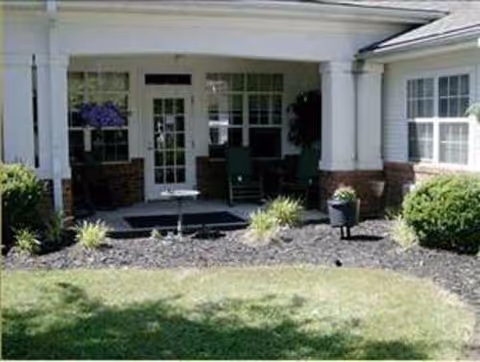 Front entrance of a senior living facility with white columns and porch seating.
