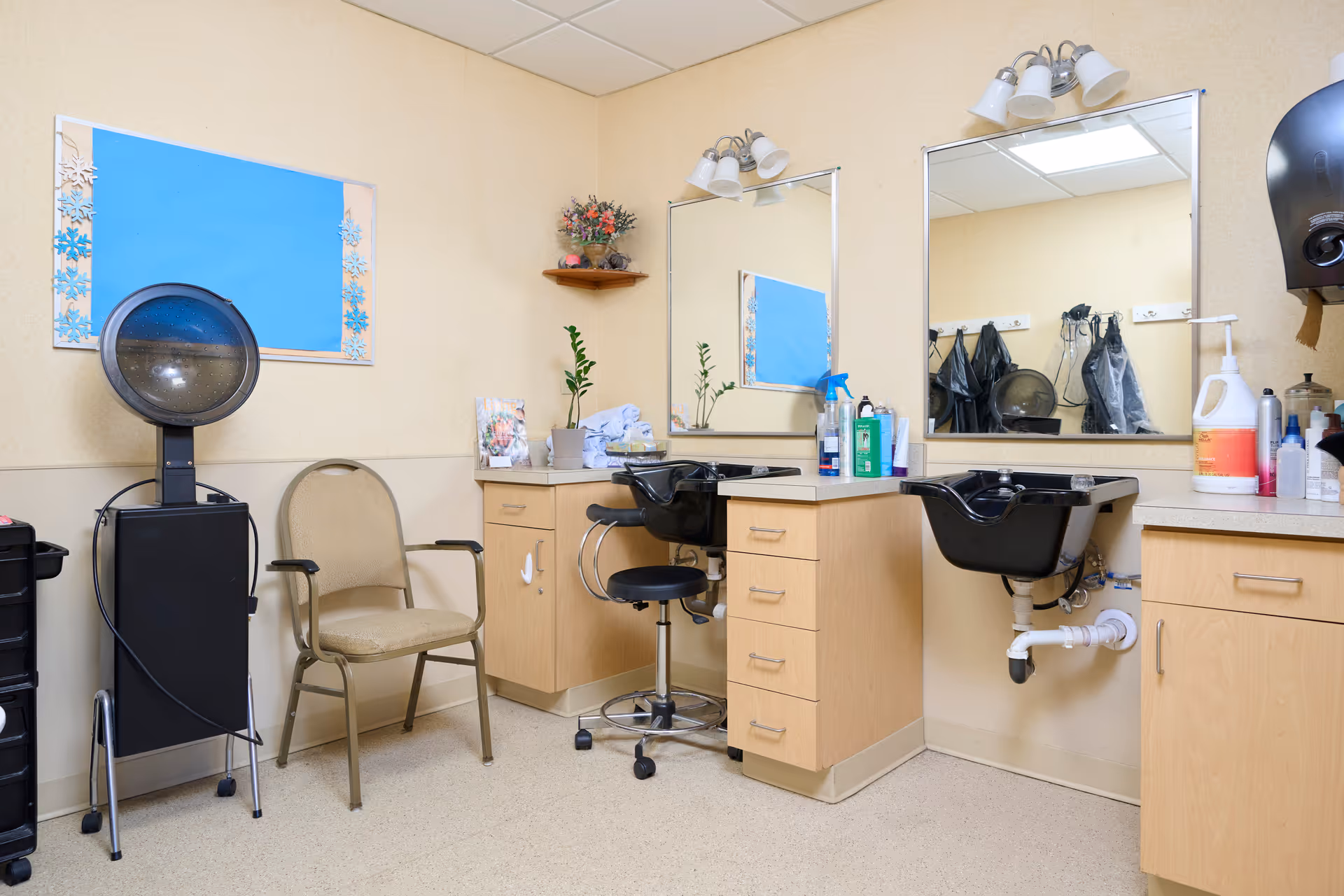 Interior salon area with two hair-washing sinks, mirrors, styling chairs, a hooded hair dryer and cabinets.