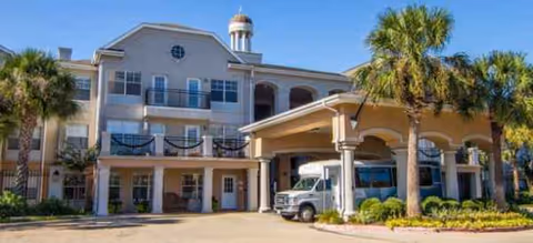 Front exterior of Brookdale Clear Lake senior living building with palm trees and a covered entrance.