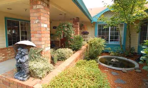 Regency Woodland exterior courtyard with brick walls, plants, and a small fountain.