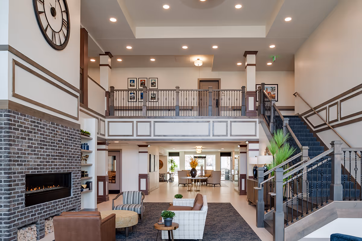 Spacious two-story lobby with seating areas, a brick fireplace, and a central staircase leading to an upper balcony.