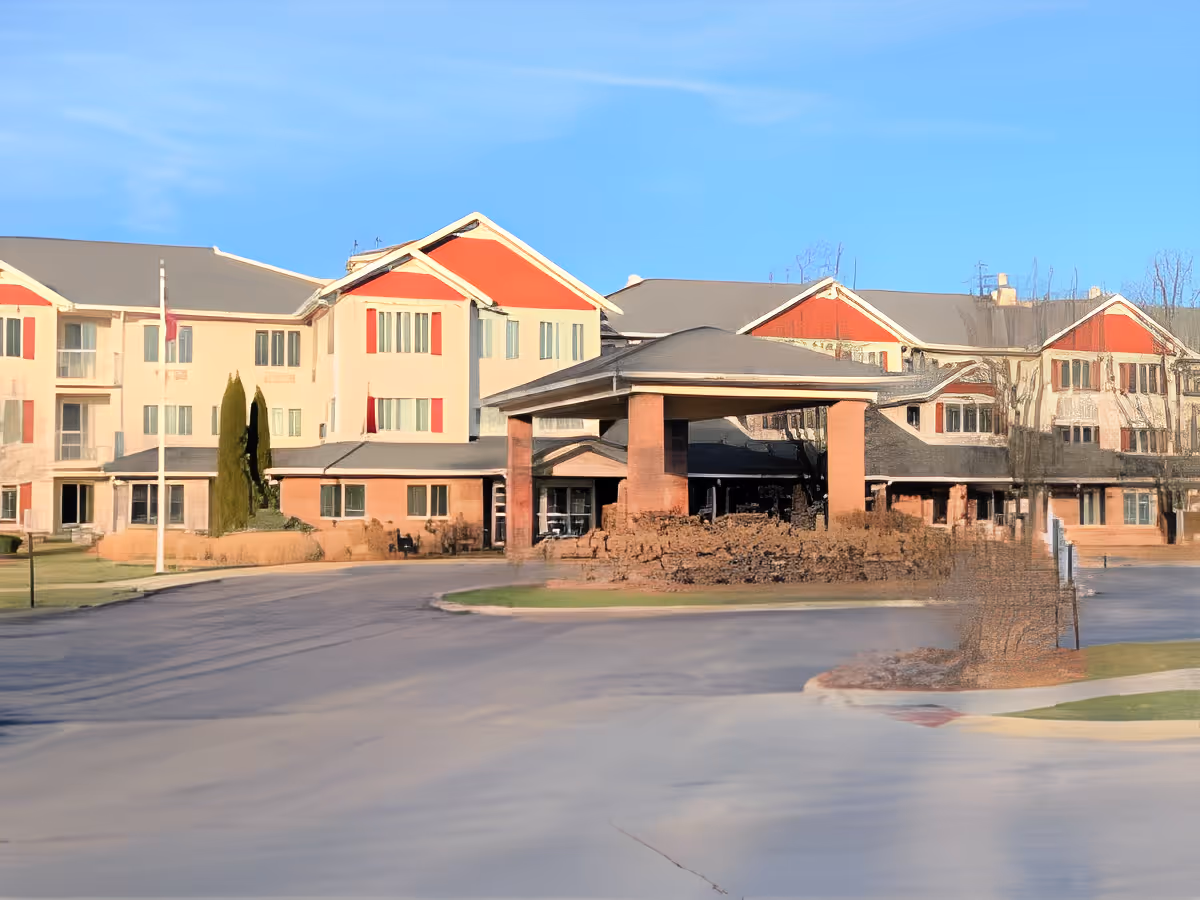 Exterior front view of a multi-story senior living building with a covered porte-cochere entrance and circular driveway.