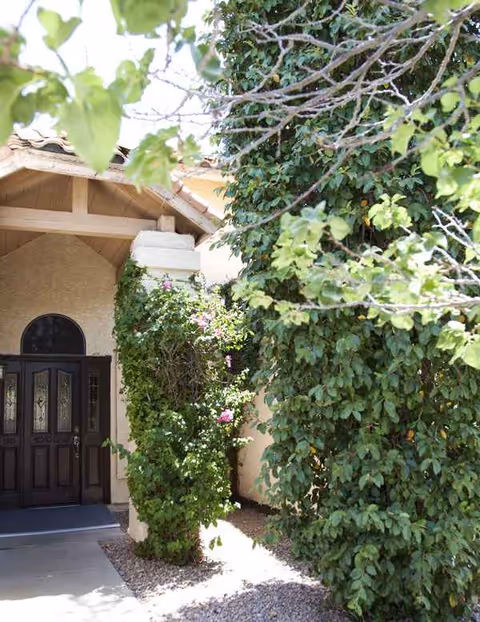 Entryway of a senior living facility with a wooden door and lush vines