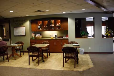 A senior living dining area with tables, chairs, and a beverage counter.