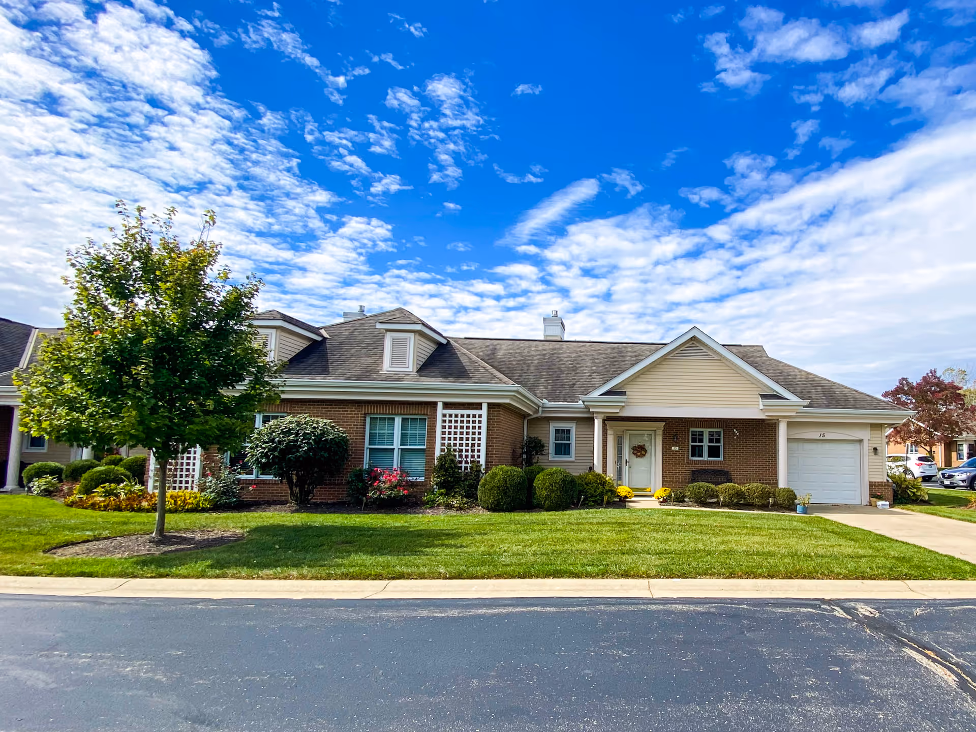 Front view of a brick and siding house with manicured lawn and tree