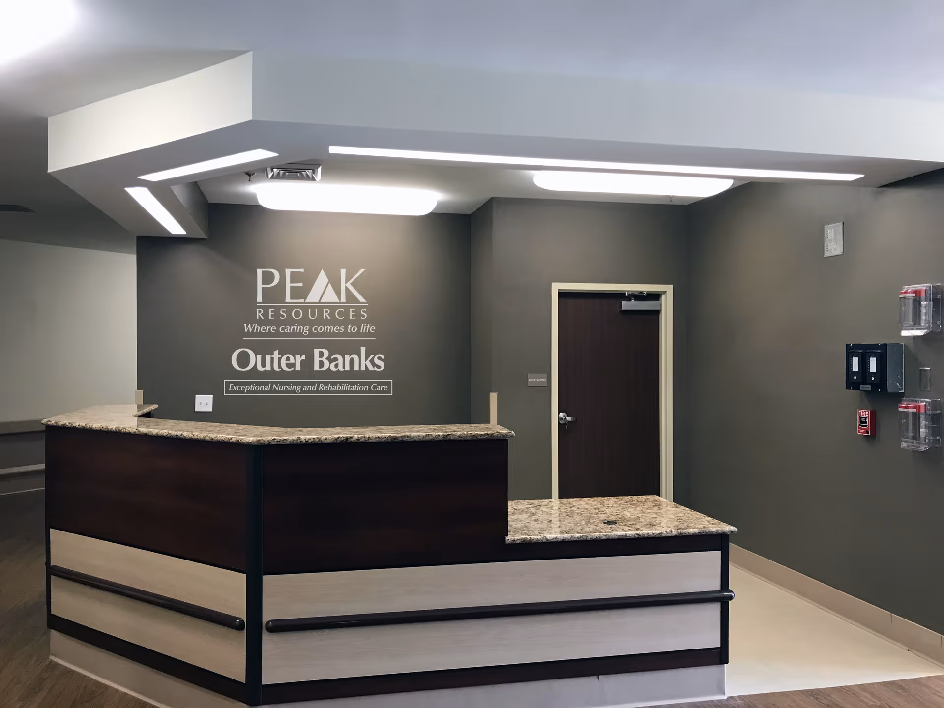 Reception desk and wall signage reading 'PEAK RESOURCES Outer Banks' in a nursing facility lobby.