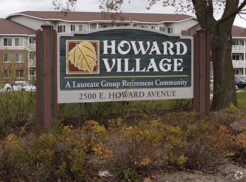 Exterior view of Howard Village sign with a building in the background and landscaping.