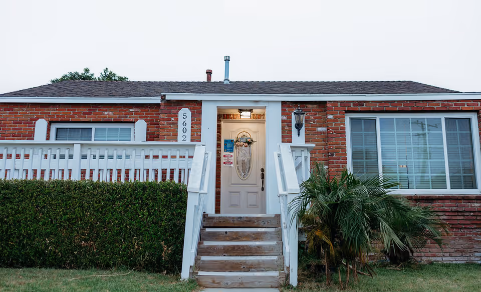 Front exterior of a single-story brick house with white porch railings, steps, and a centered front door numbered 5602.