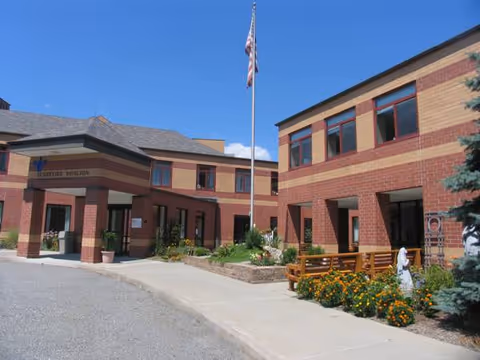 Exterior view of Mt Alverno Center's brick buildings, flagpole, and landscaped entrance.