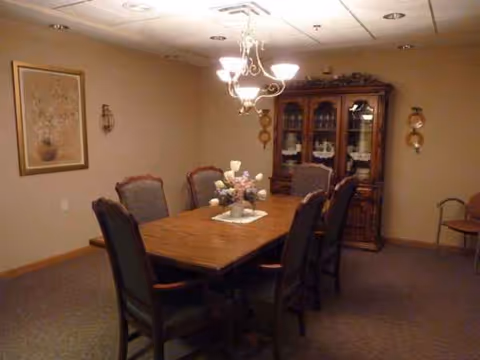 A formal dining room with a long wooden table, eight chairs, chandelier, and china cabinet.
