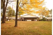 Autumn scene with a pavilion, trees, and a grassy lawn at a senior residence.