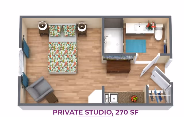Top-down view of a private studio apartment floor plan featuring a bedroom area with a bed, two nightstands, and an armchair, a bathroom with a shower, sink, and toilet, a small kitchen area with a sink and countertop, and a closet space. The floor is wood, and the bed has a colorful floral bedspread.