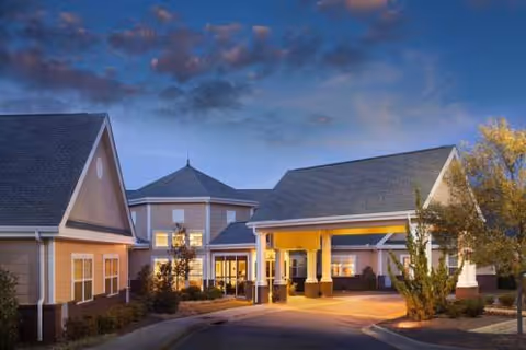 Front exterior view of Redstone Village senior living facility at dusk with entrance canopy