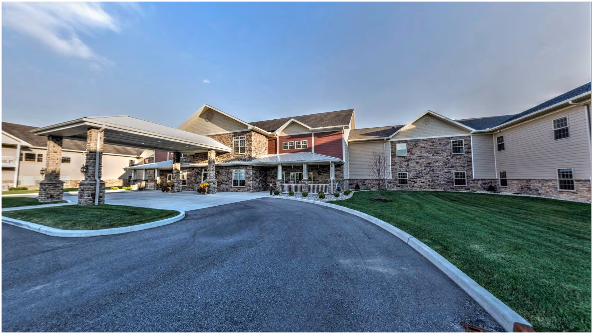 Front exterior view of a Primrose Retirement Community Mishawaka building with a covered driveway and manicured lawn.