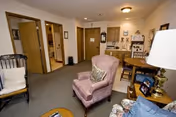 Cozy living room with upholstered armchairs, a small dining table, lamp, and open doorways to adjacent rooms.