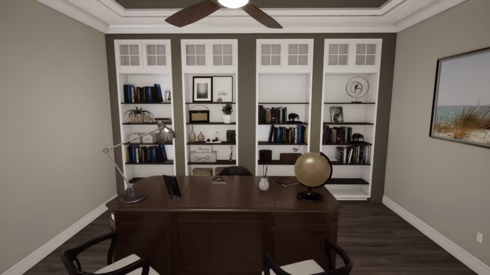 A well-lit office space with a large wooden desk in the center. On the desk are a globe, a desk lamp, a small vase, and some books. Behind the desk are built-in white bookshelves filled with books, decorative items, and framed pictures. The walls are painted beige, and there is a framed beach landscape picture on the right wall. The floor is dark wood, and a ceiling fan with wooden blades is visible above.