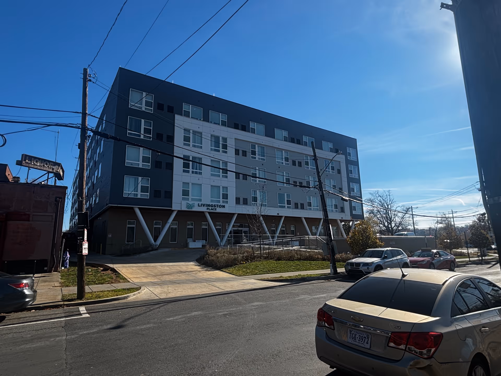 Street view of the multi-story Livingston Place senior living building with parked cars in front under a clear blue sky.