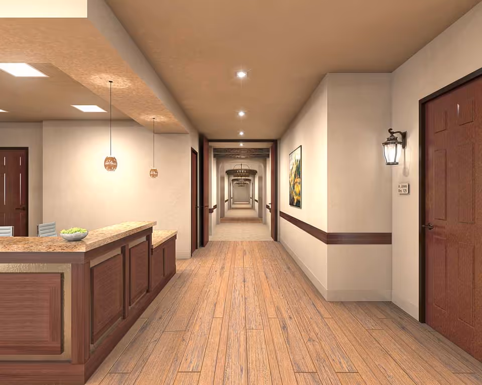 Well-lit interior hallway with a reception desk on the left, wood floors, doors and artwork along the walls.