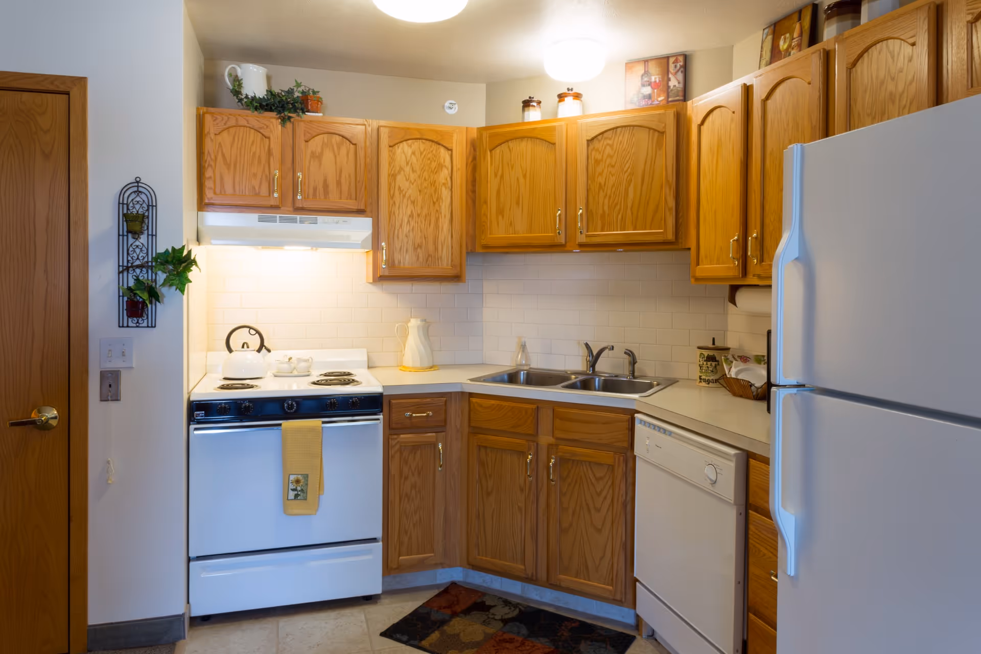 Kitchen with oak cabinets, white stove and refrigerator, dishwasher, and a double sink.