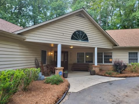 Single-story beige senior care home with a covered front porch and benches.
