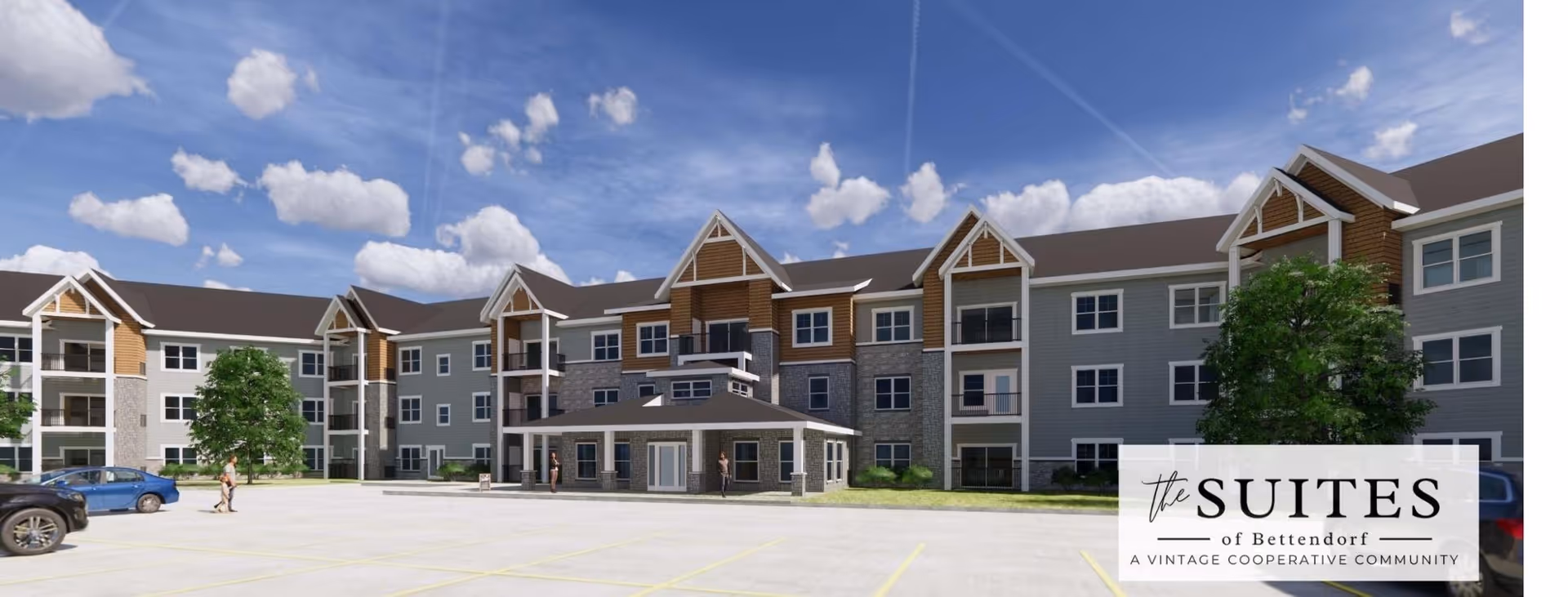 Exterior view of The Suites of Bettendorf, a three-story senior living building with a large parking lot in front, under a partly cloudy blue sky.