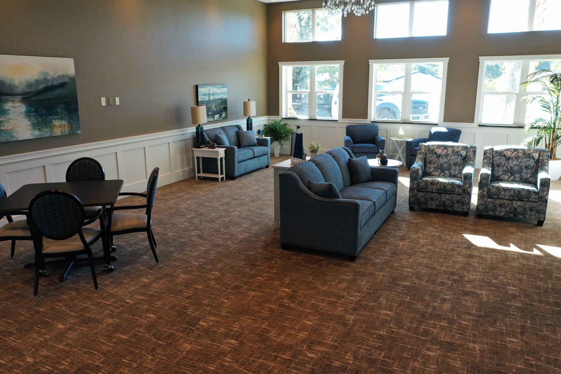 Bright lounge area with blue sofas, patterned chairs, and large windows.