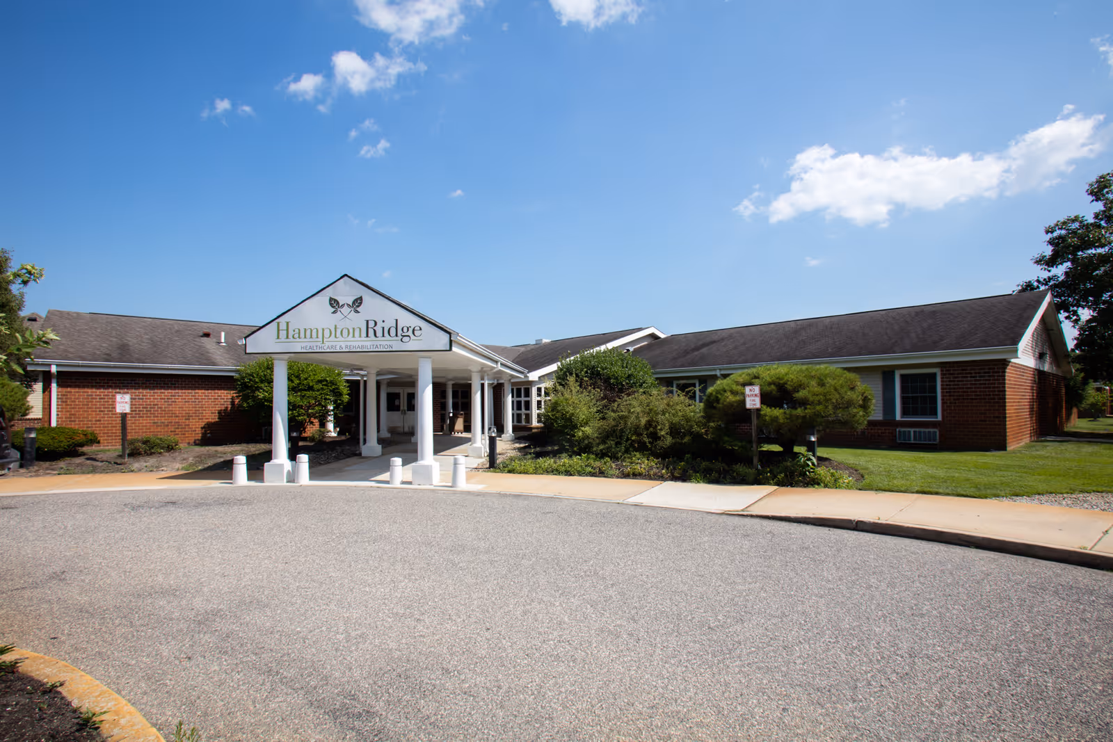 Front entrance of Hampton Ridge Healthcare & Rehabilitation, a single-story brick building with a covered porte-cochère and landscaped grounds.
