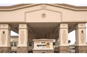 Entrance of Aperion Care Oak Lawn facility showing a covered drop-off area with beige columns and stone accents. The facility name and address number 9401 are displayed on a sign beneath the covered entrance.