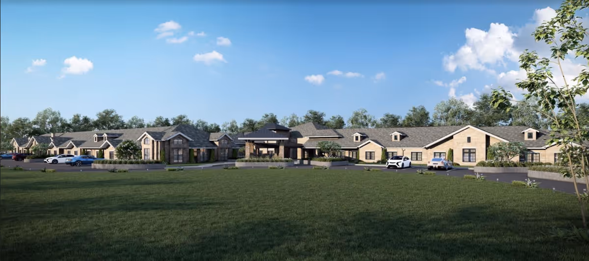 Long, single-story senior living building with brick facade, parking lot, and green front lawn.
