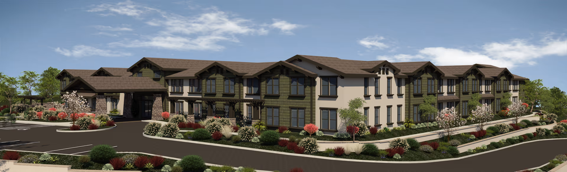 Exterior view of a large two-story senior living facility building with a brown roof and green and beige walls, surrounded by landscaped gardens with bushes and flowers, under a blue sky with some clouds.
