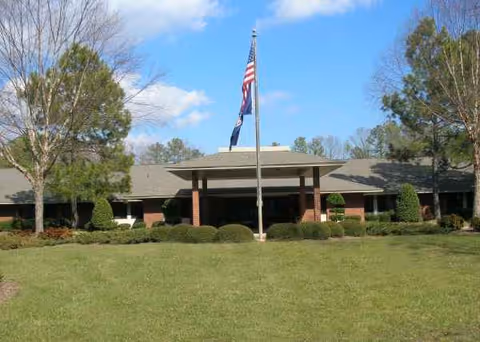 Exterior view of a single-story convalescent center with flagpole and lawn.