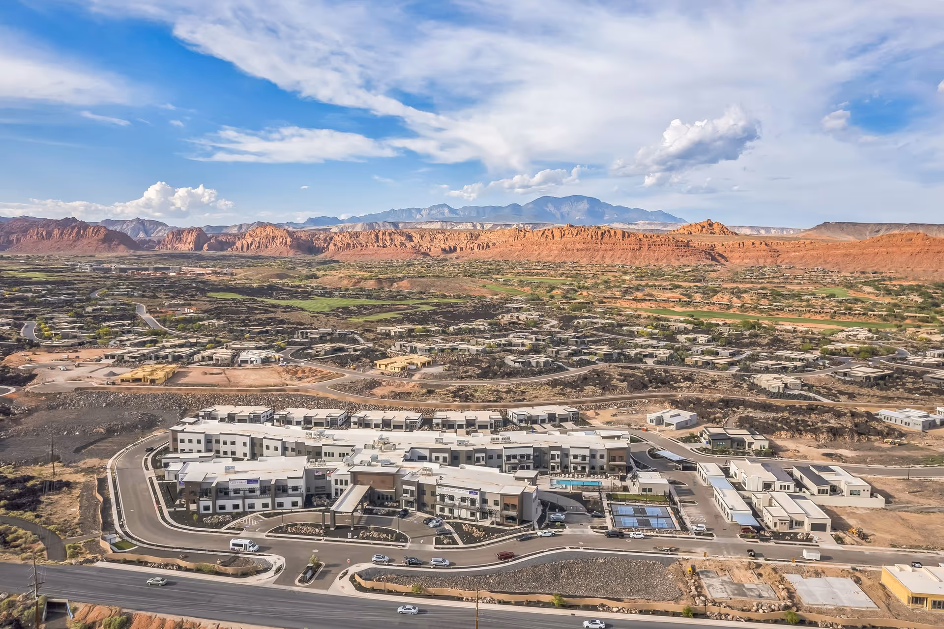 Aerial view of the Snow Canyon Retirement Community complex set in a desert landscape with red rock mesas and mountains in the background.