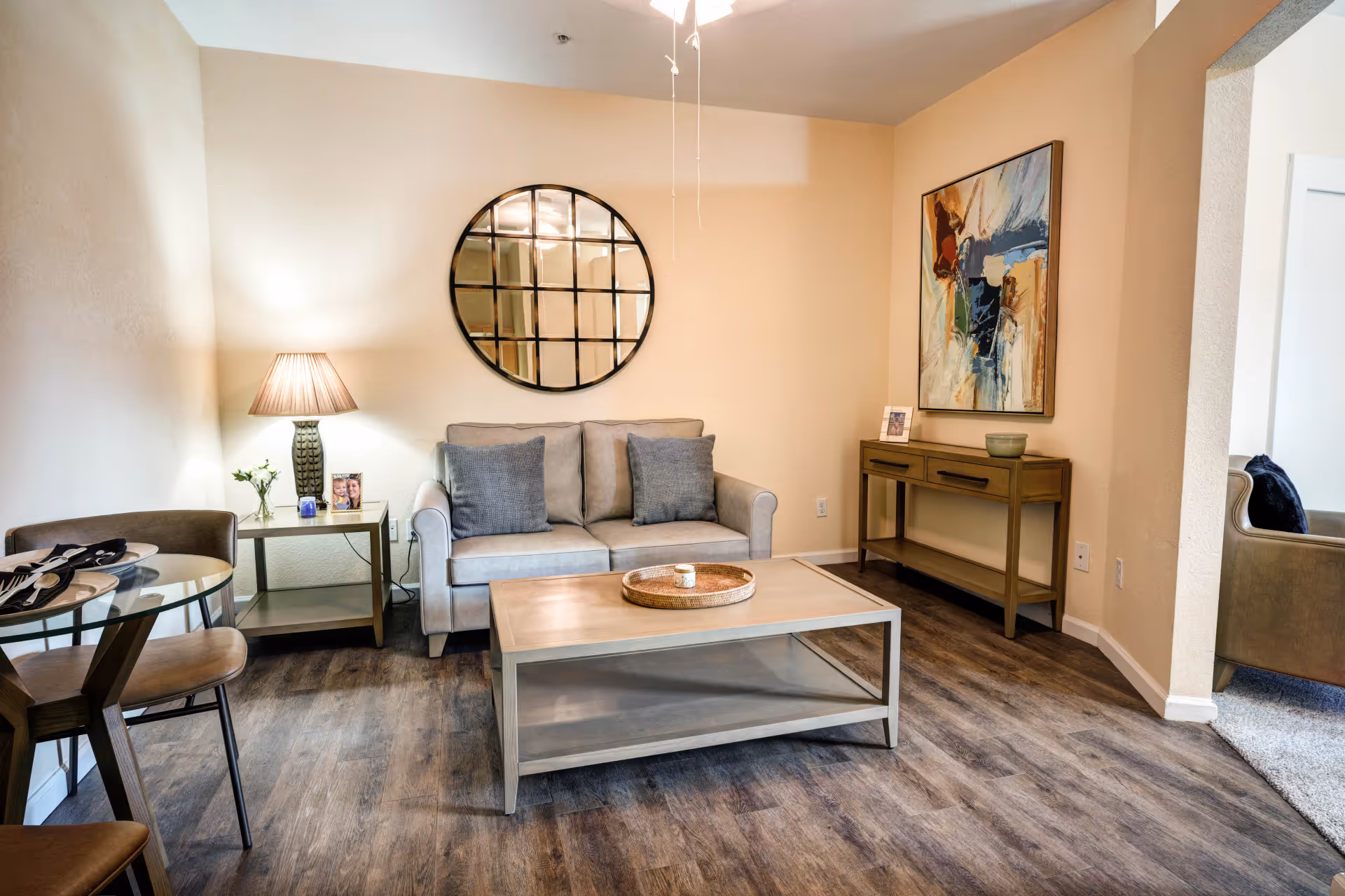 Comfortable living room with a sofa, coffee table, round wall mirror, side table, console table and a small dining nook.