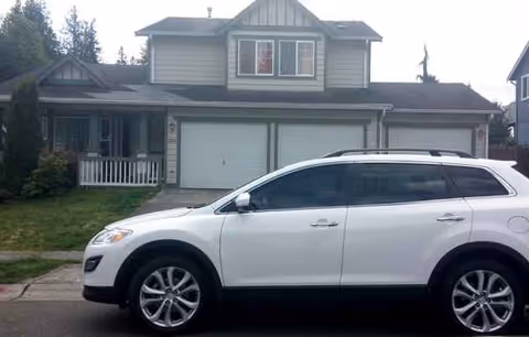 Residential two-story home with a white SUV parked in front and a two-car garage.