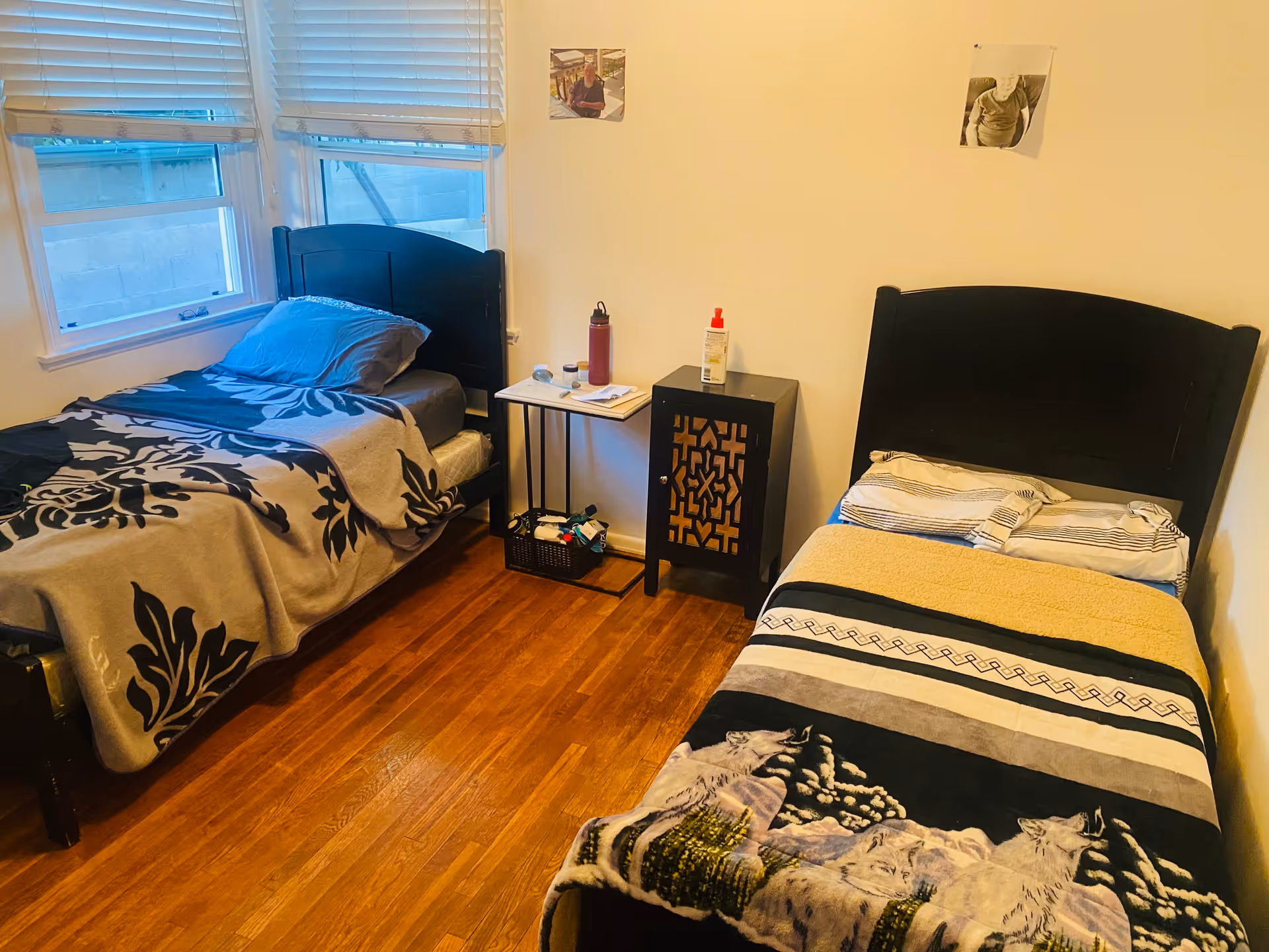 Small bedroom with two twin beds, a shared nightstand and a window with blinds.