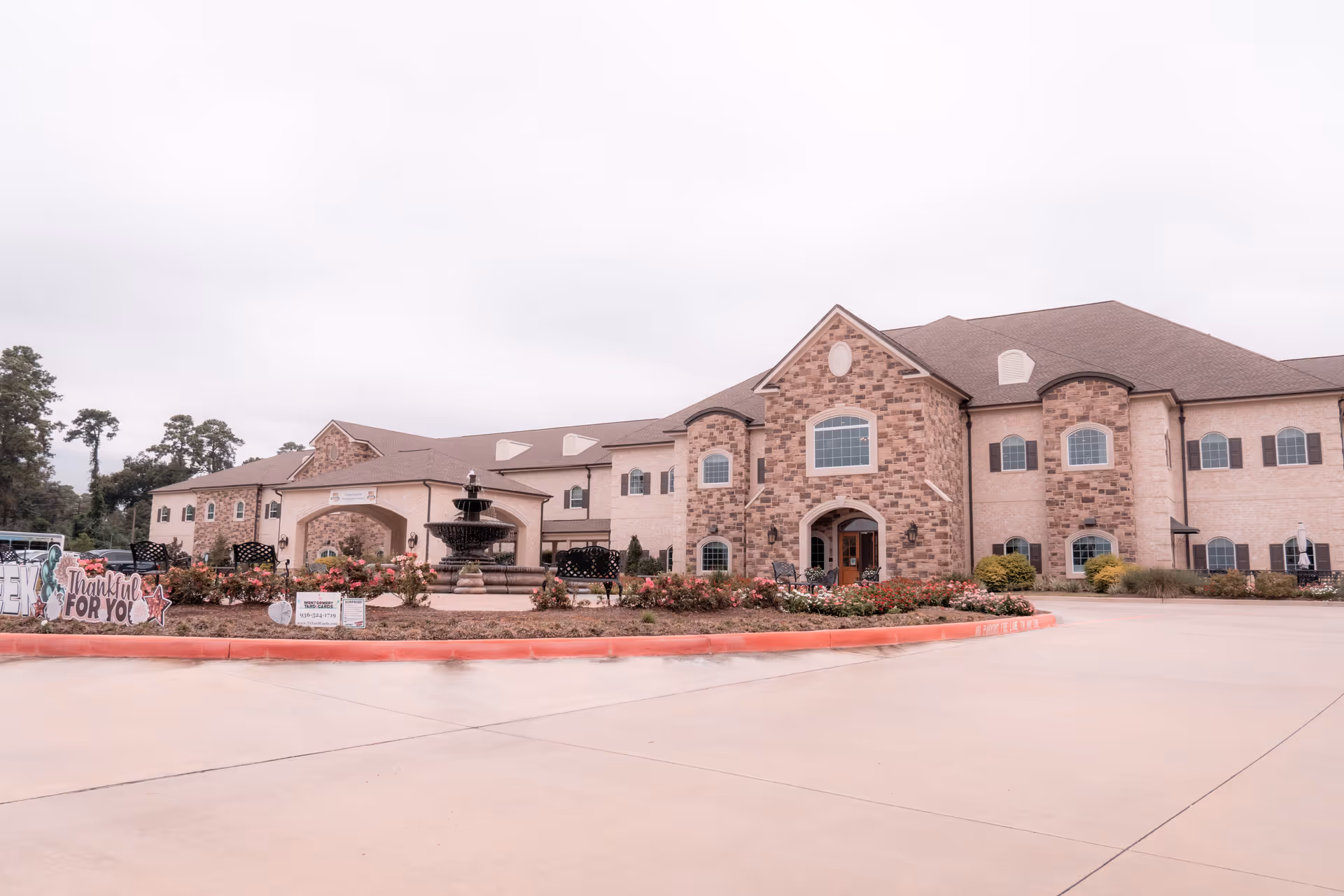 Front exterior of Worthington Manor, a large two-story brick building with a central fountain and landscaped driveway.