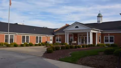 Brick exterior of Louisville East Post Acute Care with a covered entrance and landscaped shrubs.